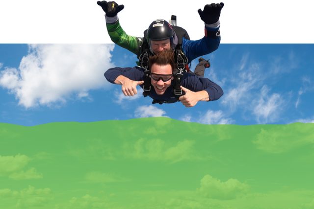 man giving thumbs up attached to skydiving instructor during tandem skydiving