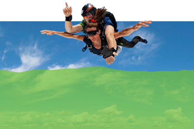 Photo with decorative green filter added of a tandem skydiver and instructor in freefall