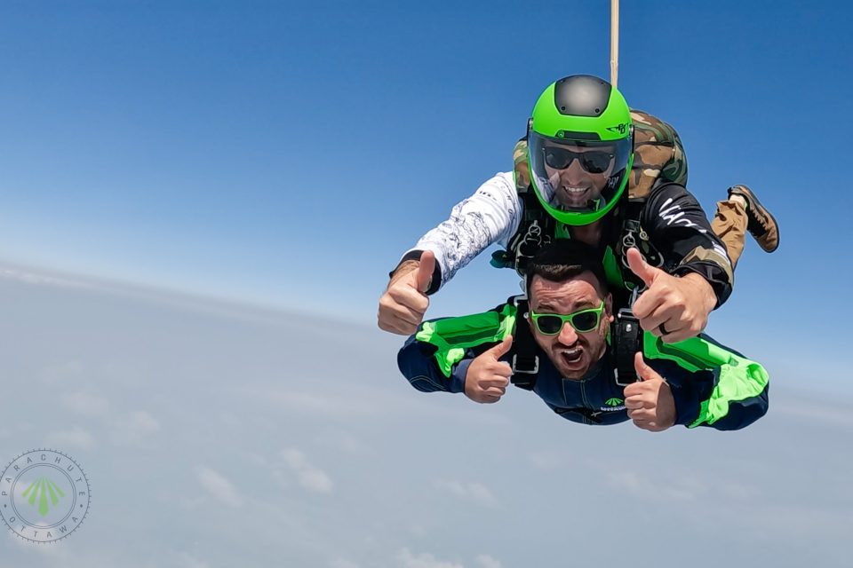 man tandem skydiving with thumbs up
