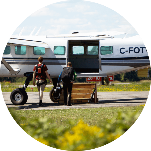 Two skydivers preparing to board and aircraft on the runway at Parachute Ottawa in Arnprior, ON