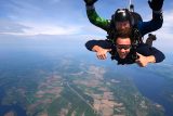 Male tandem skydiving student giving two thumbs up to camera while in freefall