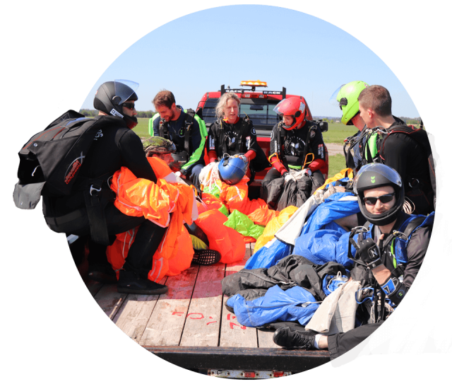 A group of experienced skydivers with colorful parachutes riding in the back of a truck at Parachute Ottawa