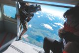 Outside skydiving videographer positioning himself in the doorway of an airplane at altitude preparing to capture a tandem skydiving student's exit.