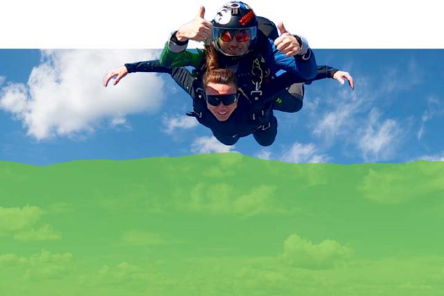 Photo with decorative green filter added of a tandem skydiver and instructor in freefall