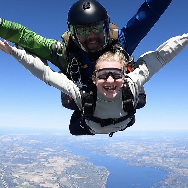 Close up of a tandem skydiving student and instructor smiling for camera while in freefall over Parachute Ottawa skydiving centre
