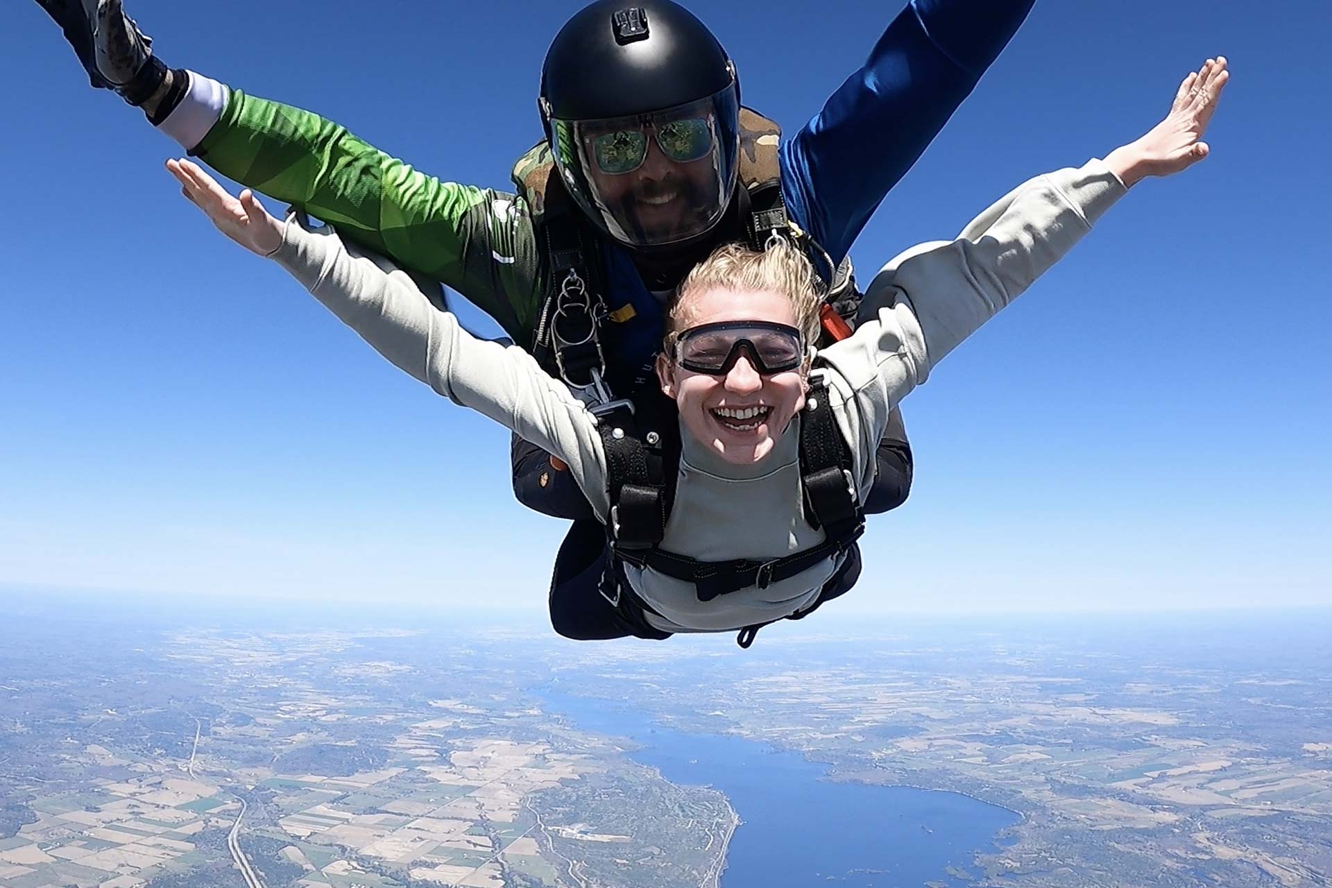 Close up of a tandem skydiving student and instructor smiling for camera while in freefall over Parachute Ottawa skydiving centre