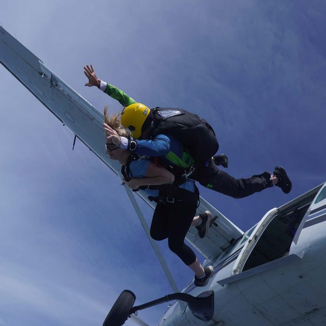 Tandem skydiving student and instructor exiting an airplane above Parachute Ottawa