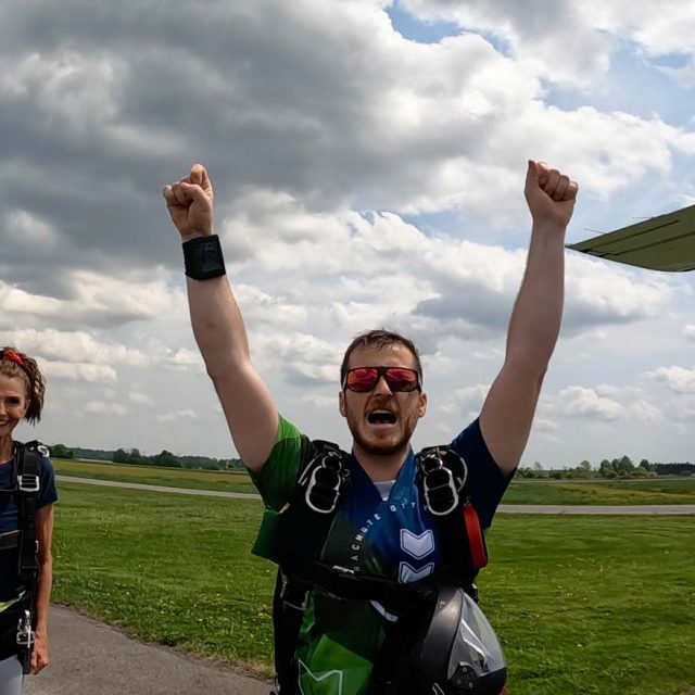 Male skydiver celebrating after a jump with his arms in the air