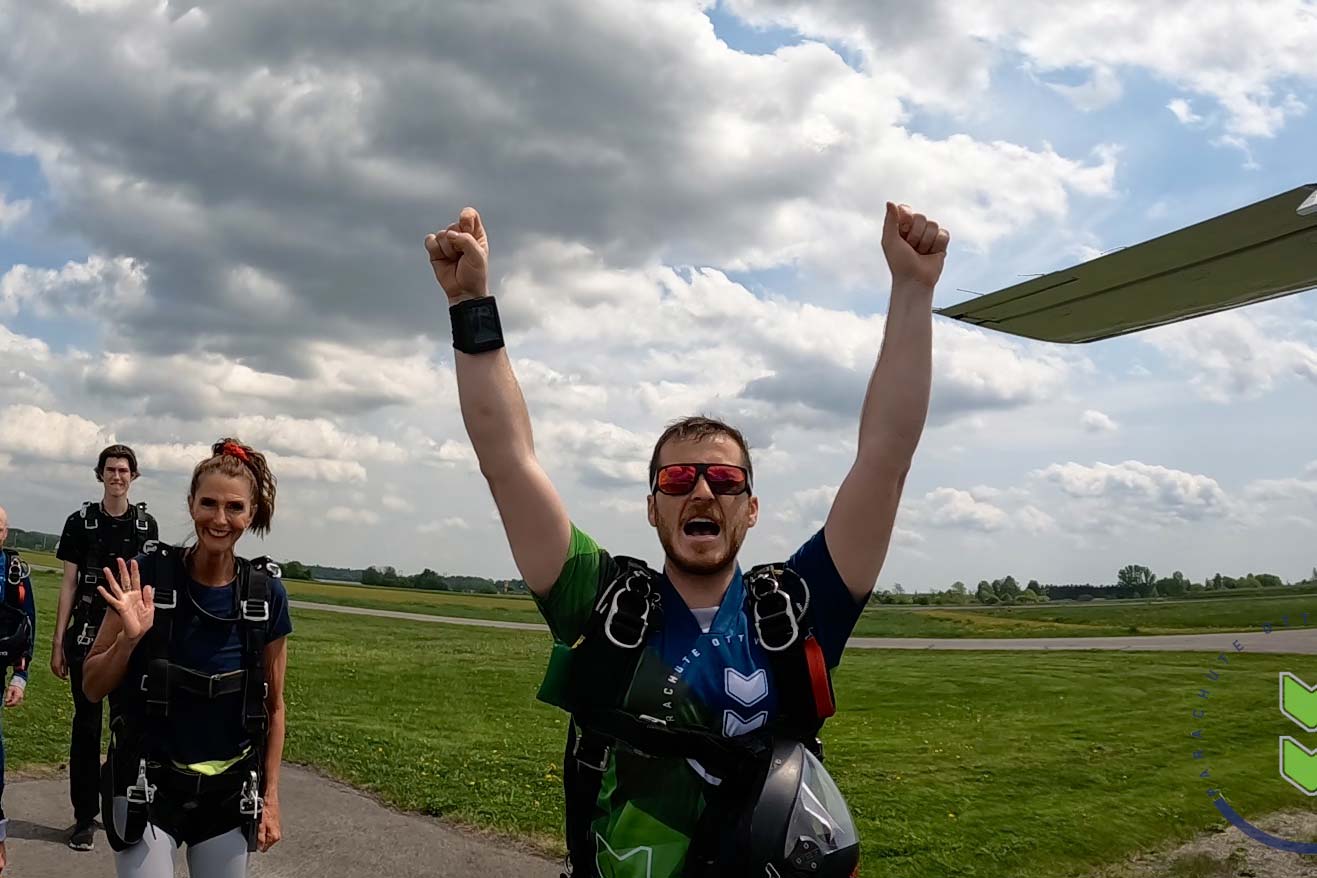 Male skydiver celebrating after a jump with his arms in the air