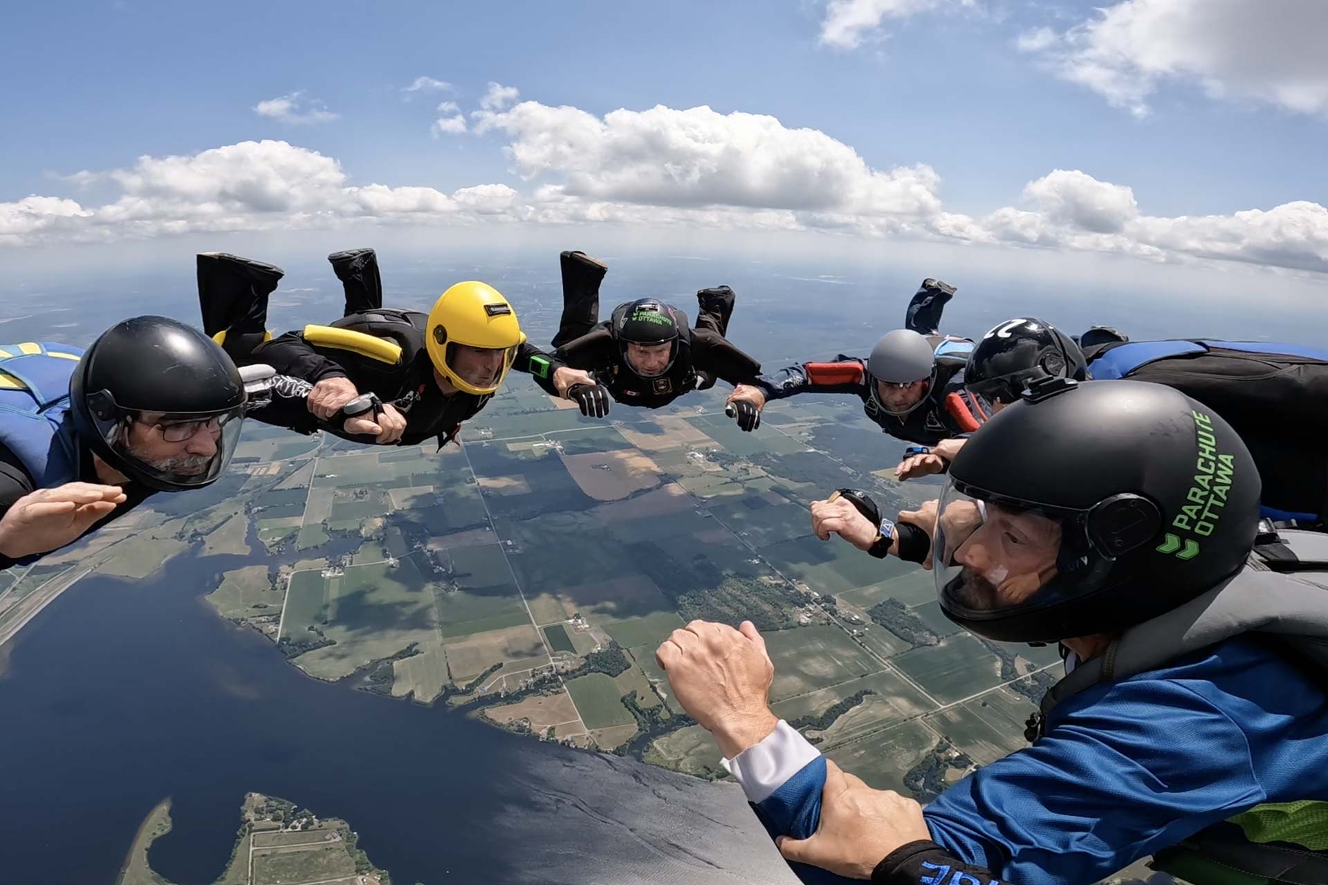 Licensed skydivers wearing a helmet in freefall making a formation over Parachute Ottawa