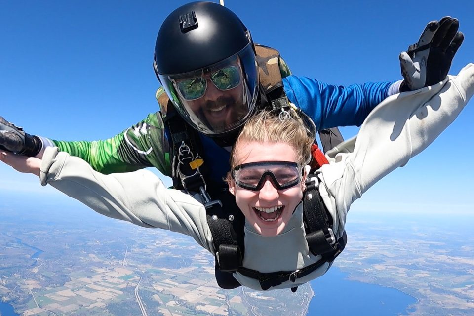 Close up of a tandem skydiving student and instructor smiling for camera while in freefall over Parachute Ottawa skydiving centre