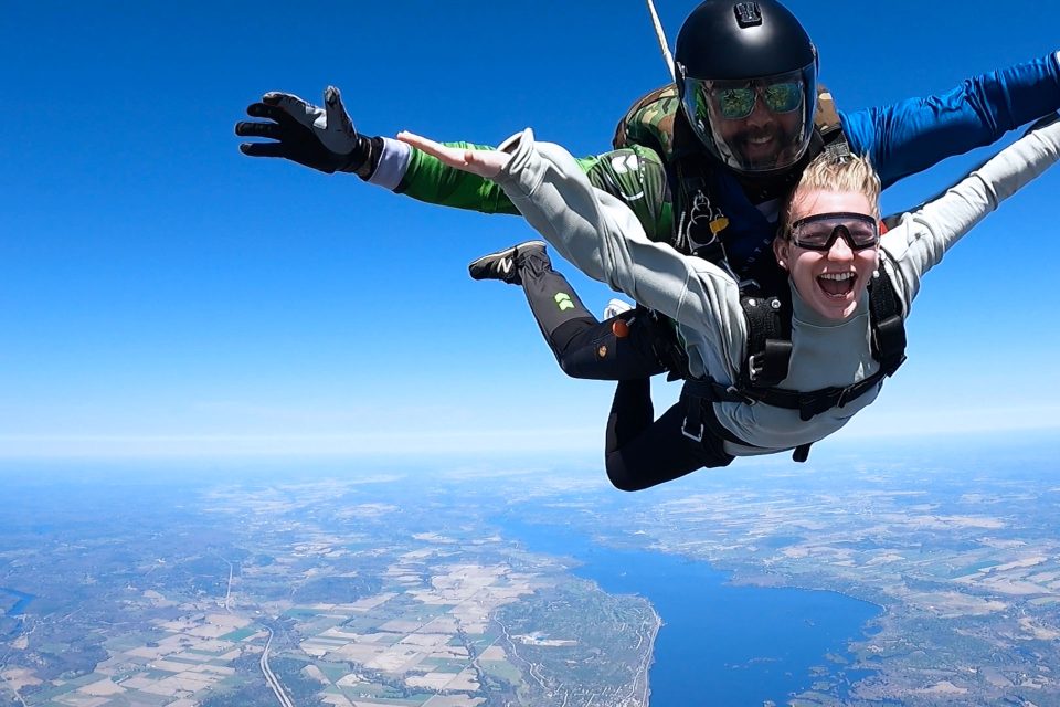 Close up of a tandem skydiving student and instructor smiling for camera while in freefall over Parachute Ottawa skydiving centre