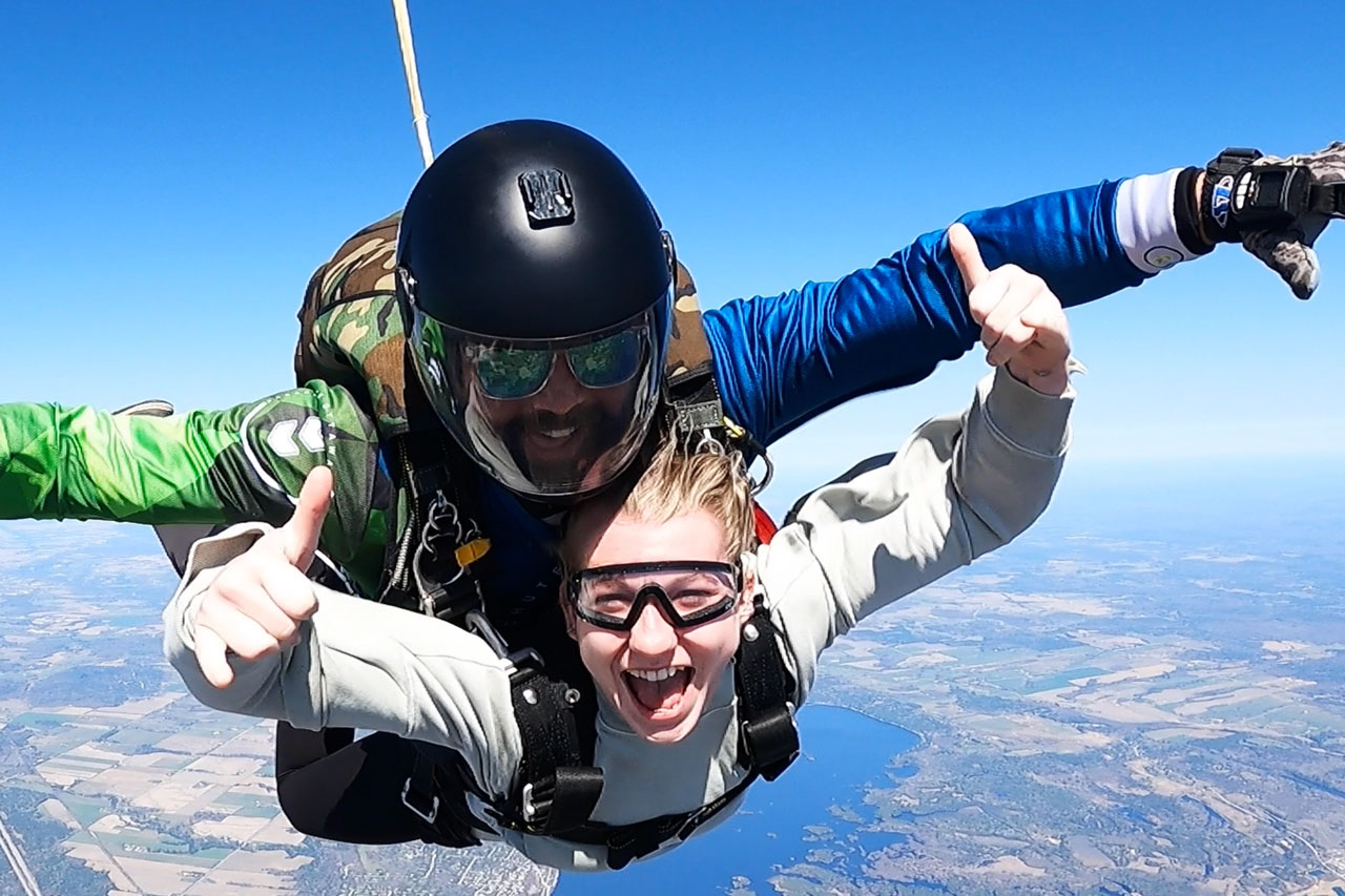 Close up of a tandem skydiving student and instructor smiling for camera while in freefall over Parachute Ottawa skydiving centre